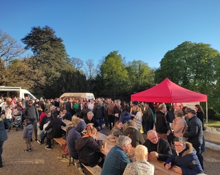 Vue d'un marché de producteurs avec des personnes attablées pour le repas en extérieur