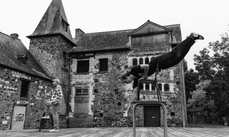 Photo du spectacle avec un acrobate et un comédien devant une demeure ancienne