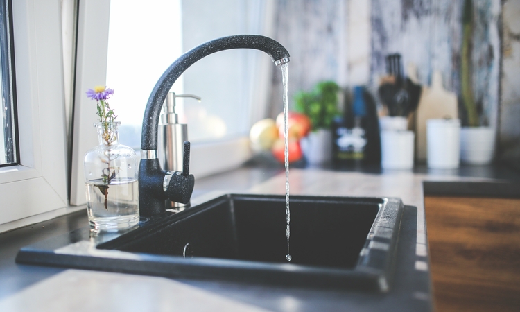 Photo d'un robinet d'un évier de cuisine  avec l'eau qui coule